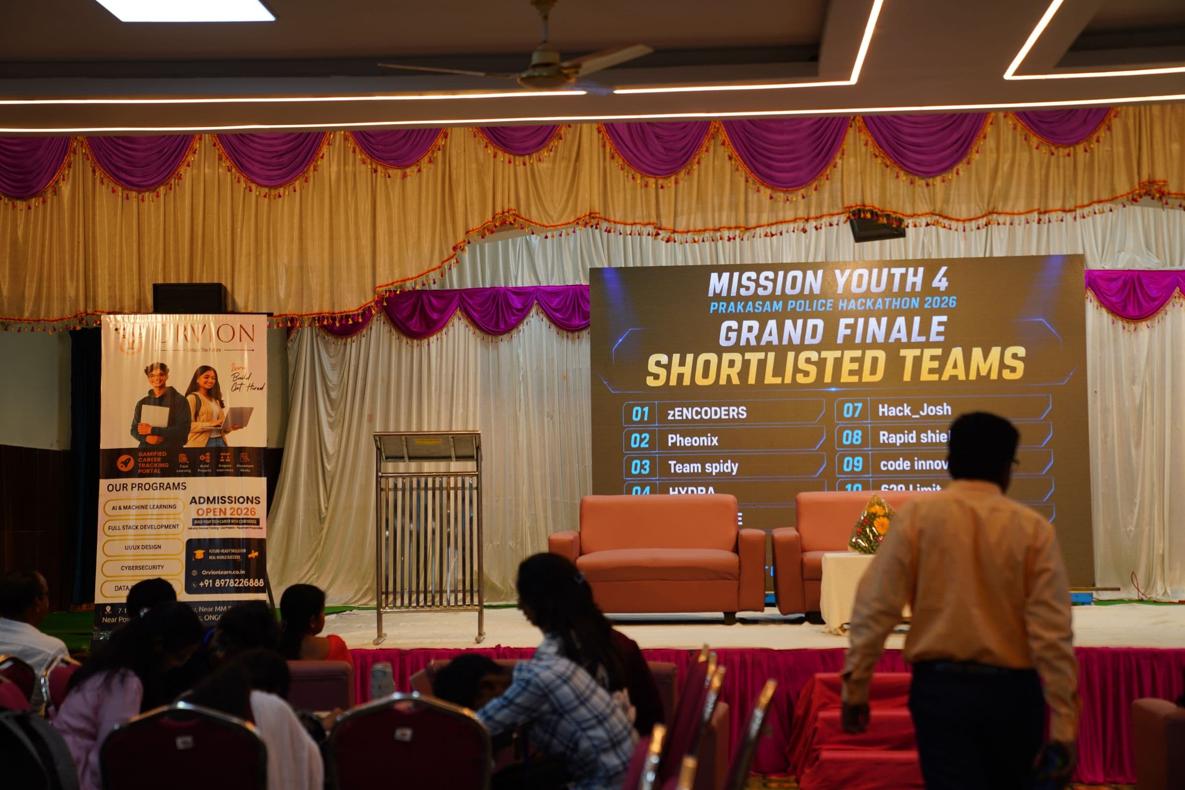 Audience seated in front of the Mission Youth 4 leaderboard screen, with the Orvion sponsor banner in the foreground